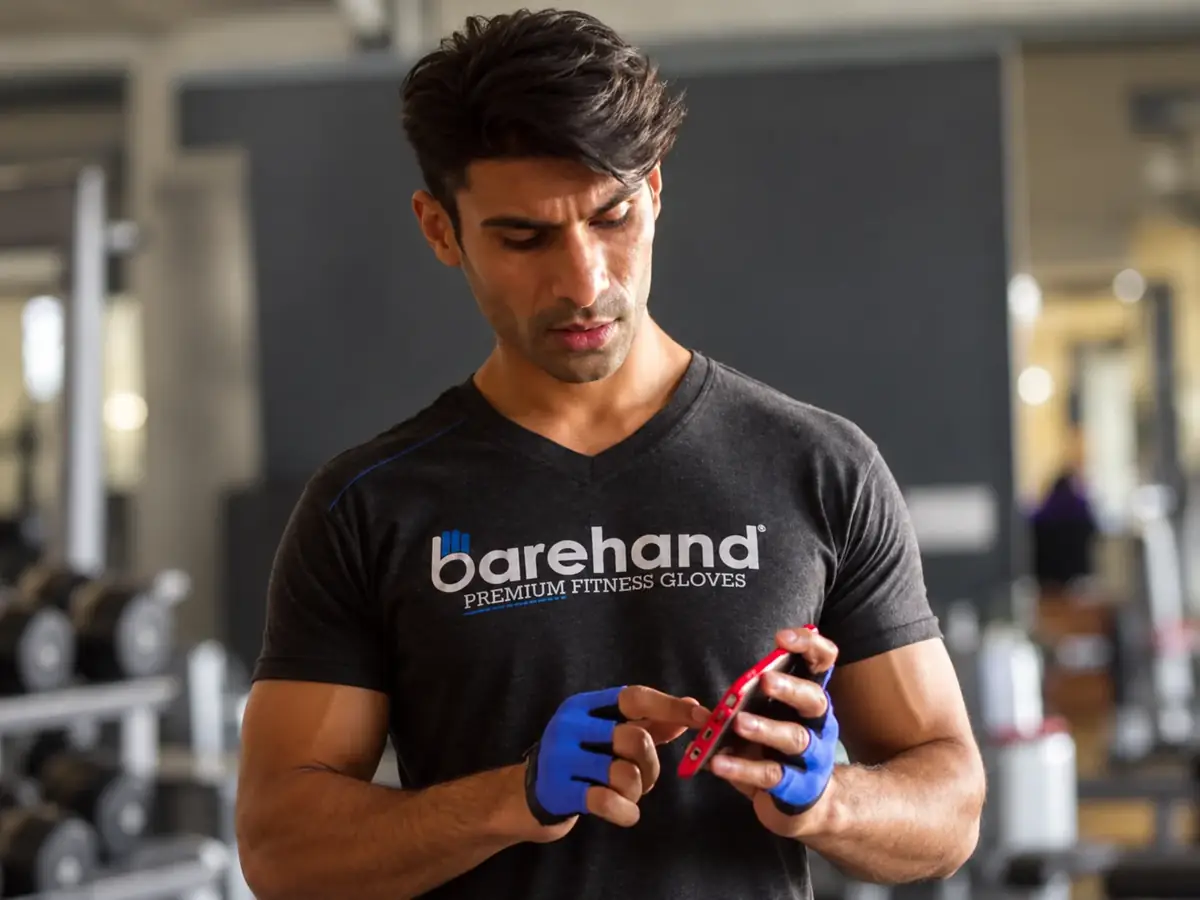 Barehand founder wearing blue fitness gloves while checking the fit in a gym.